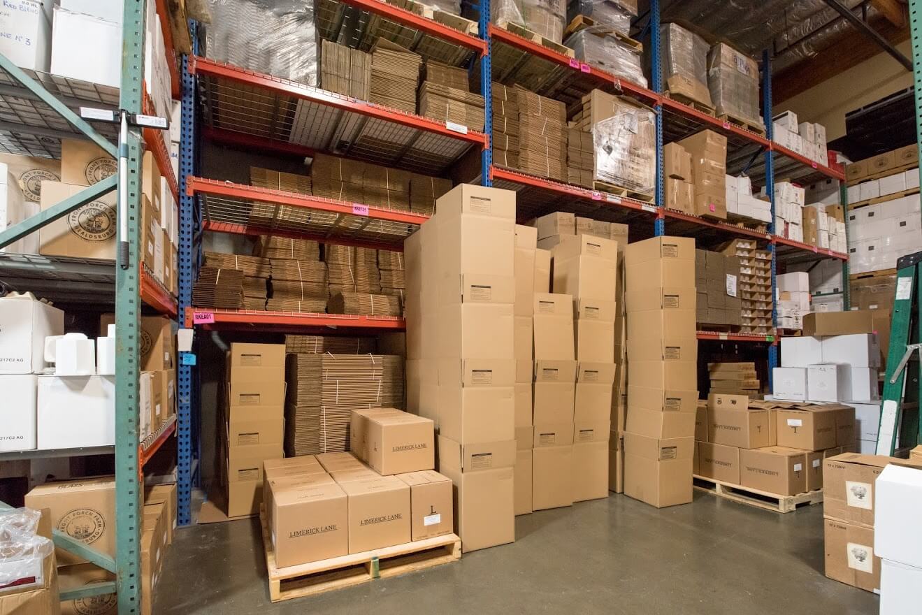 Wine cases stacked in a warehouse in front of racking.